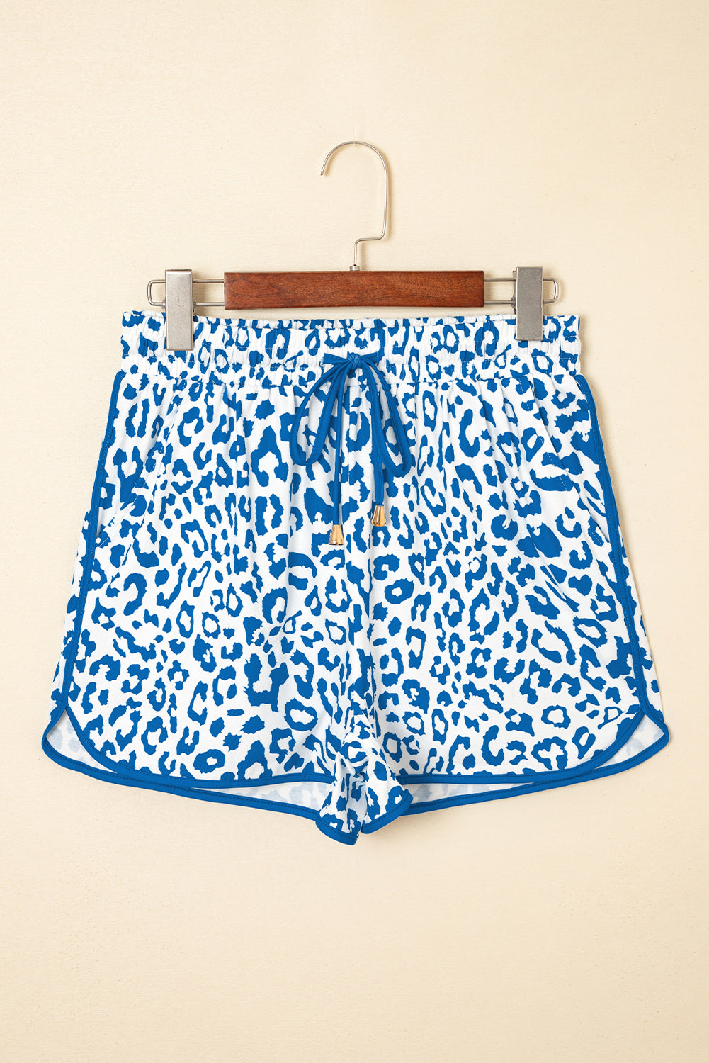Blue and white leopard print shorts on a hanger against a beige background