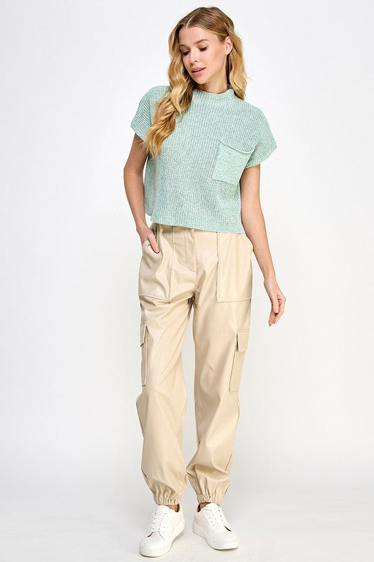 Woman wearing a light green top and beige cargo pants on a white background