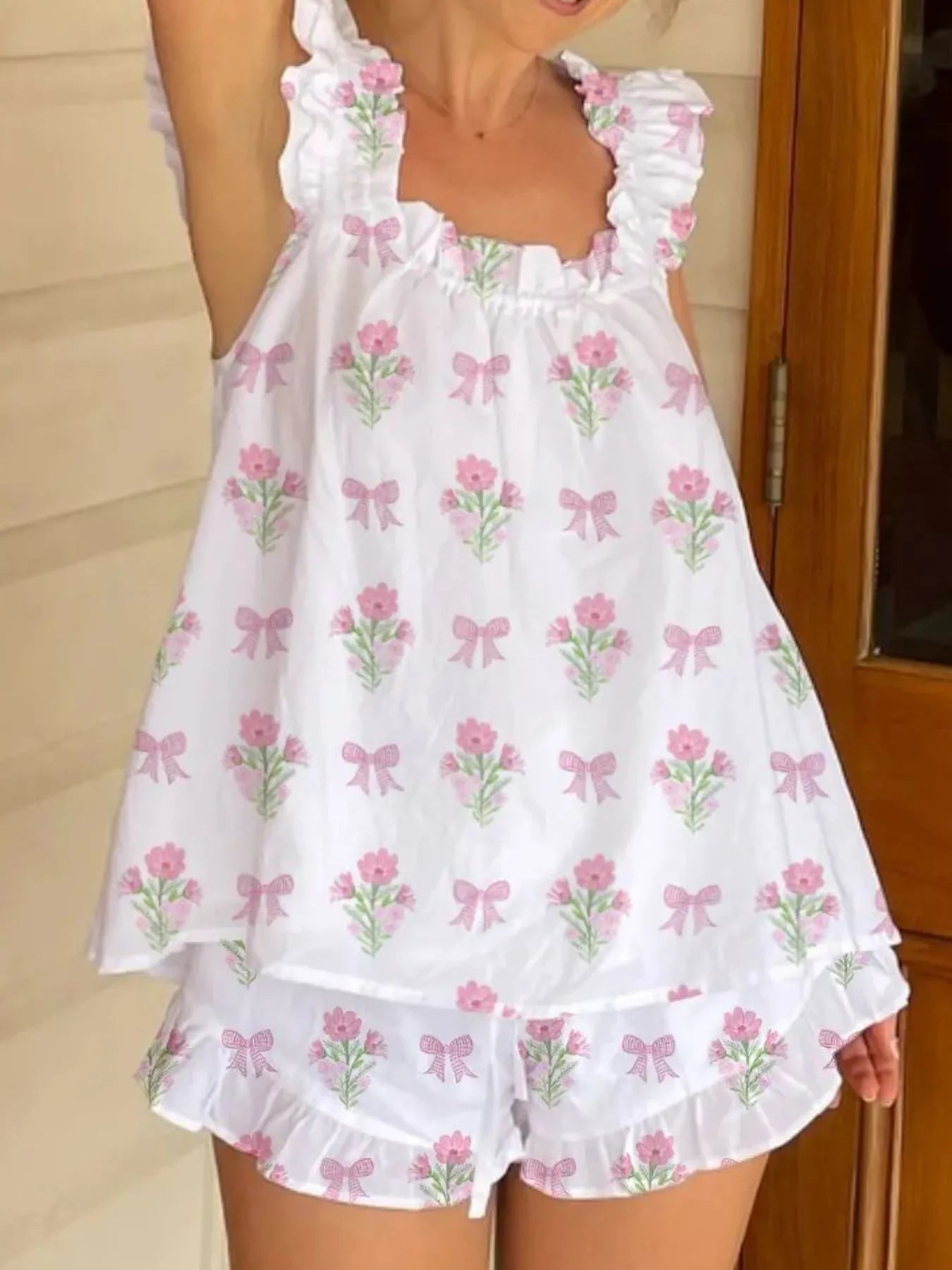 White dress with pink floral and bow patterns worn by a person.