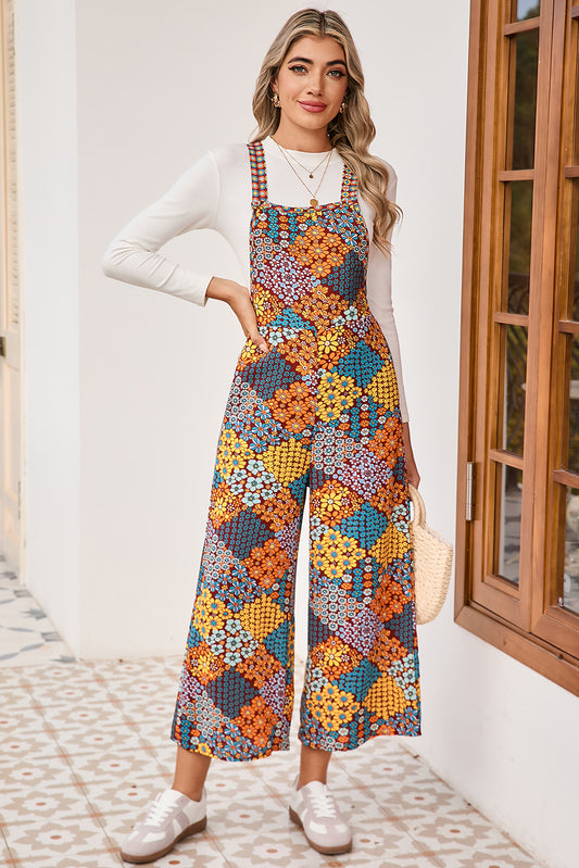 Woman wearing a colorful floral jumpsuit standing indoors.