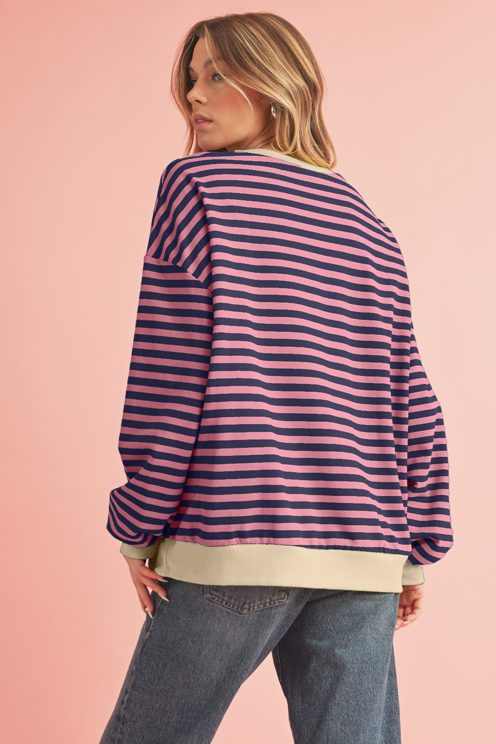 Woman wearing a striped sweater and jeans on a pink background