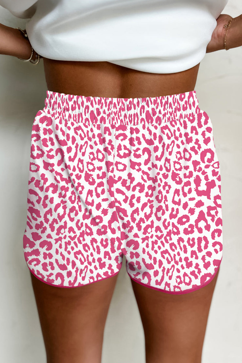 Pink leopard print shorts worn by a person on a plain background