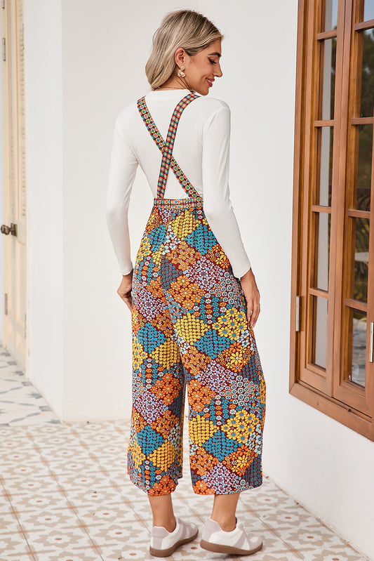Woman wearing a colorful patterned overalls standing in a room with a window.