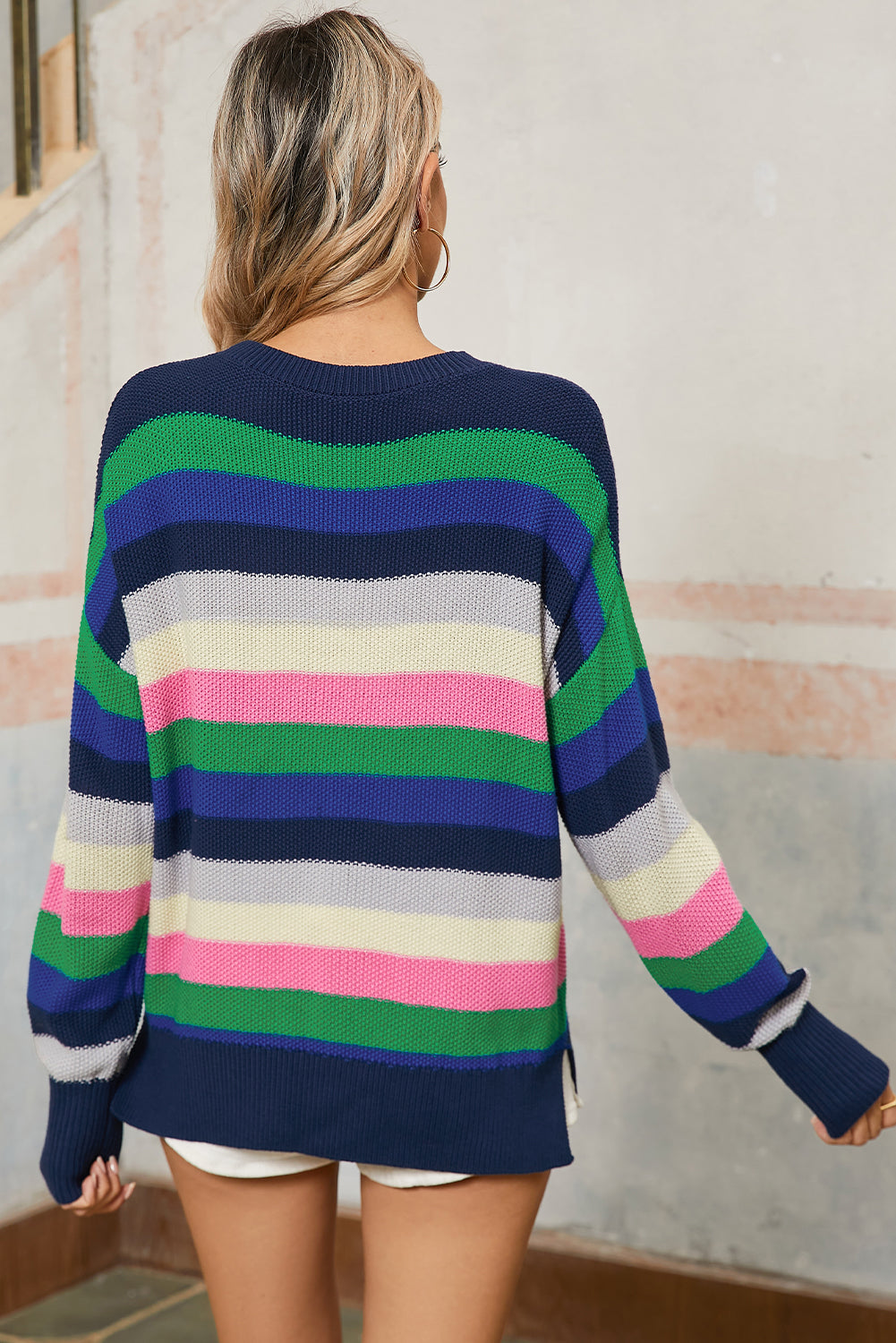 Person wearing a colorful striped sweater with a neutral background