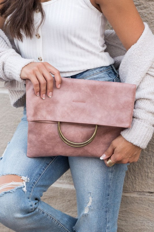 Person holding a pink clutch bag with a neutral background