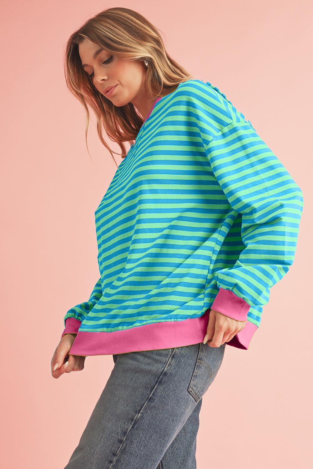 Woman wearing a colorful striped sweater against a pink background
