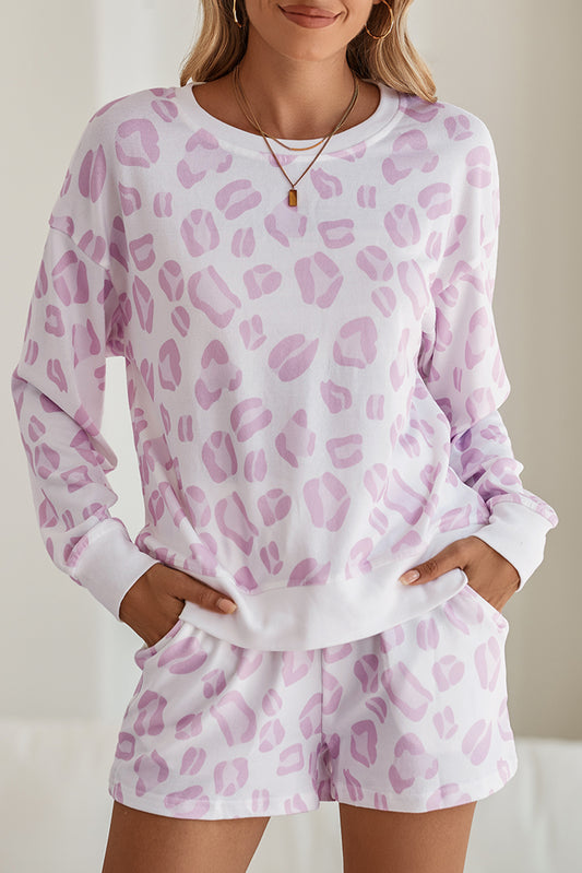 Woman wearing a pink leopard print pajama set against a neutral background