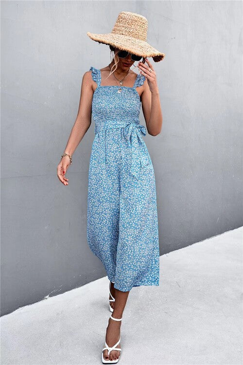 Woman wearing a blue floral dress and straw hat against a gray background