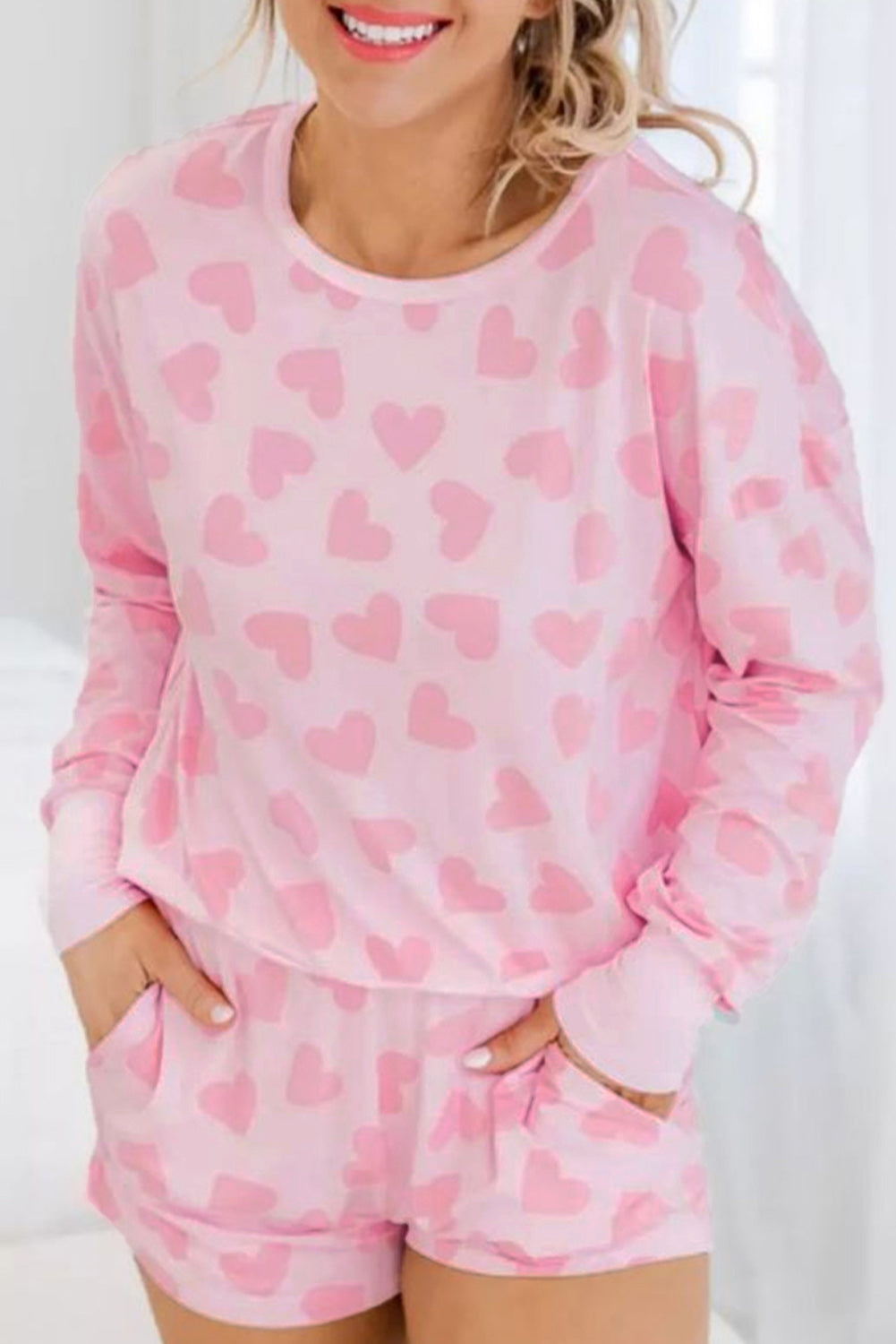 Person wearing a pink heart-patterned pajama set against a white background