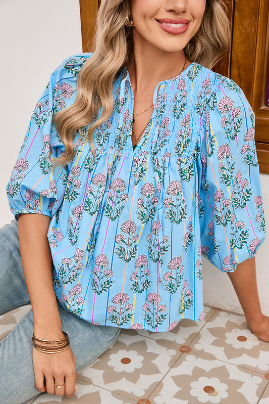 Woman wearing a blue floral blouse sitting on a patterned floor.