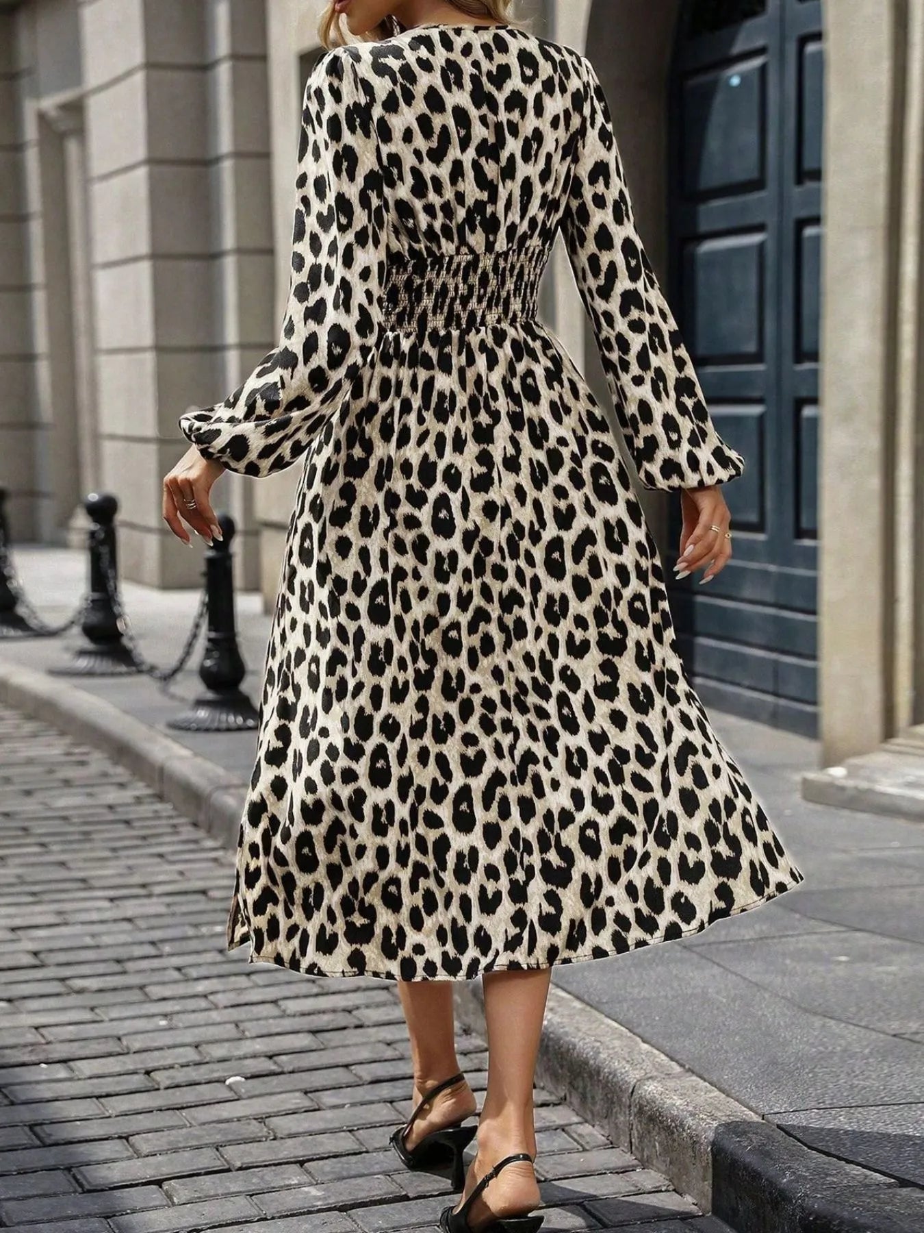 Person wearing a leopard print dress walking on a city street.