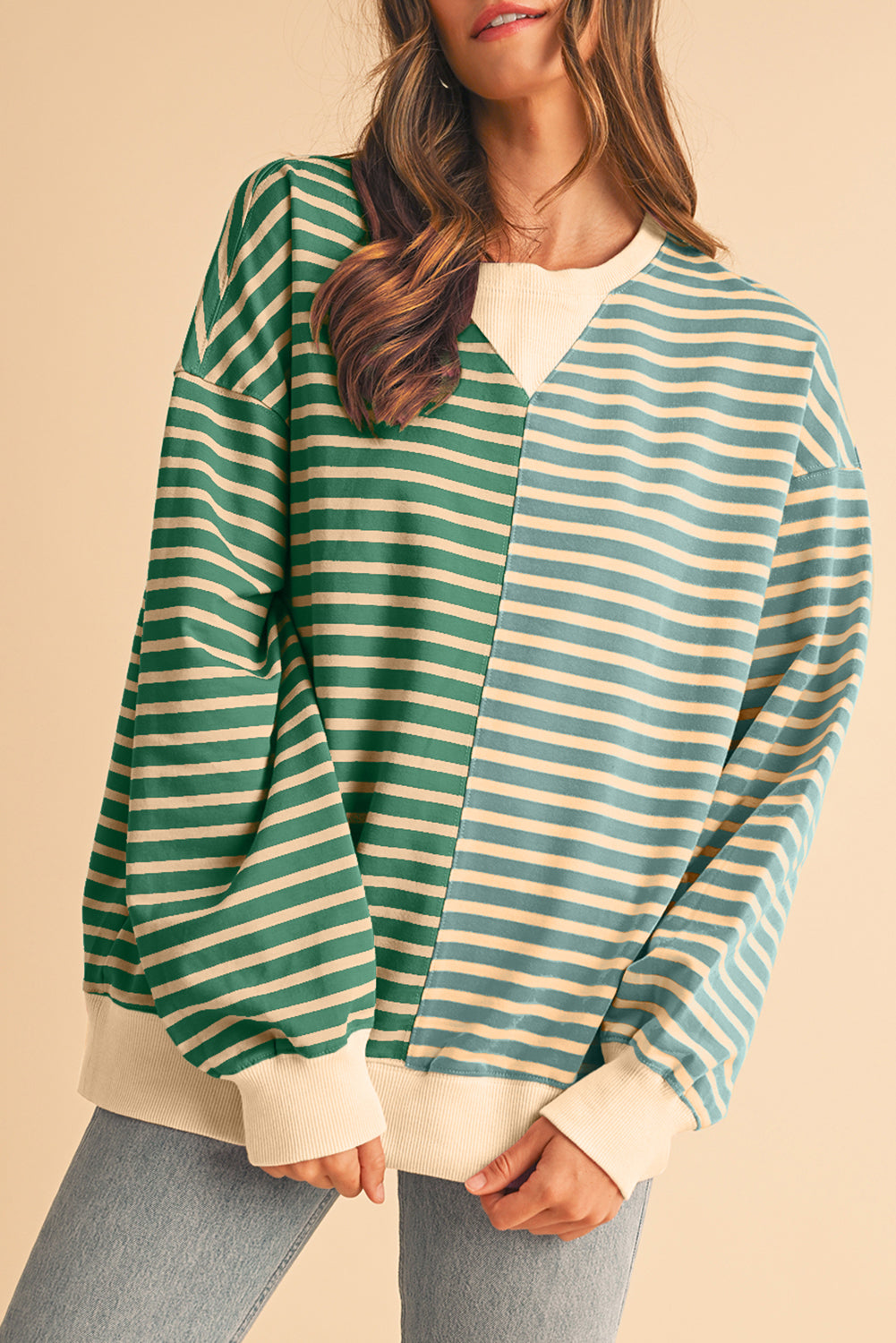 Woman wearing a green and beige striped sweater on a beige background