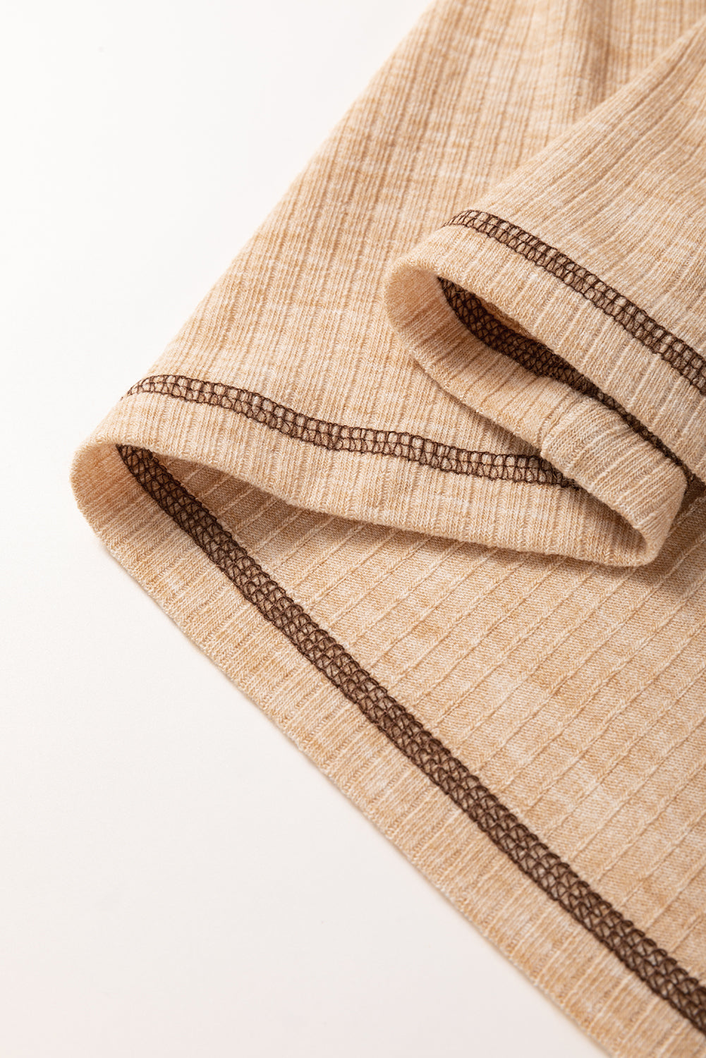 Close-up of a beige fabric with brown trim on a light background
