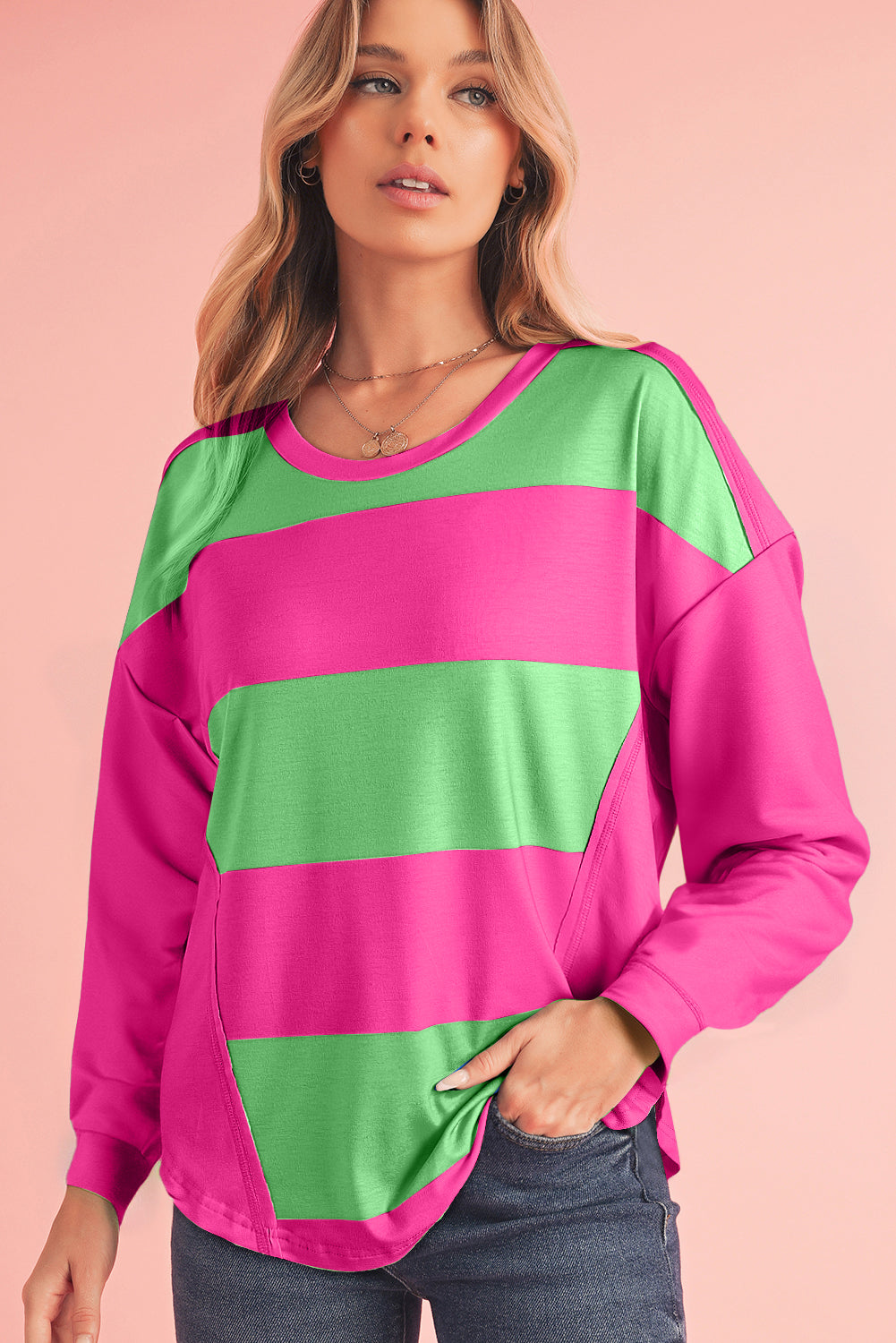 Woman wearing a pink and green striped sweater against a pink background