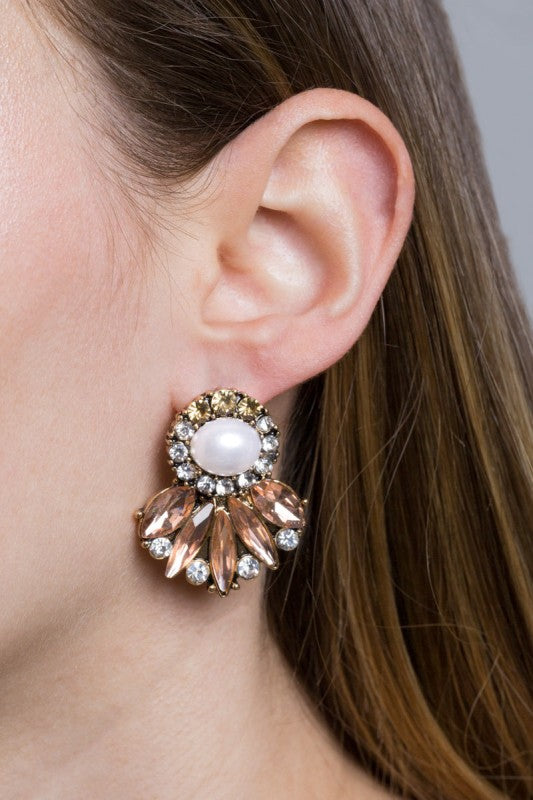 Close-up of an ear wearing a decorative earring with a pearl-like center.