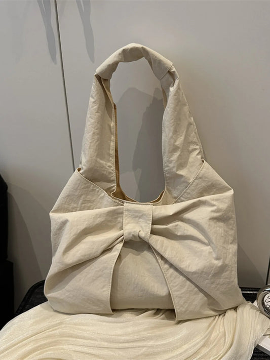 Beige tote bag with a bow detail on a neutral background