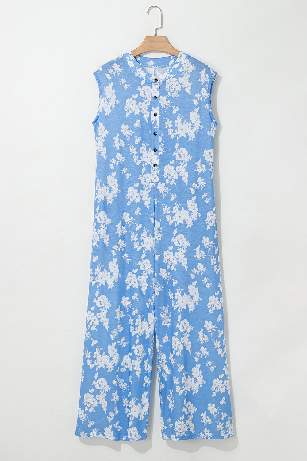 Blue floral jumpsuit on a hanger against a white background