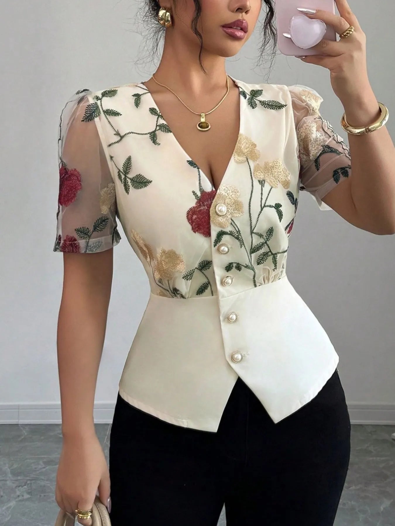 Woman wearing a floral embroidered top with a plain background