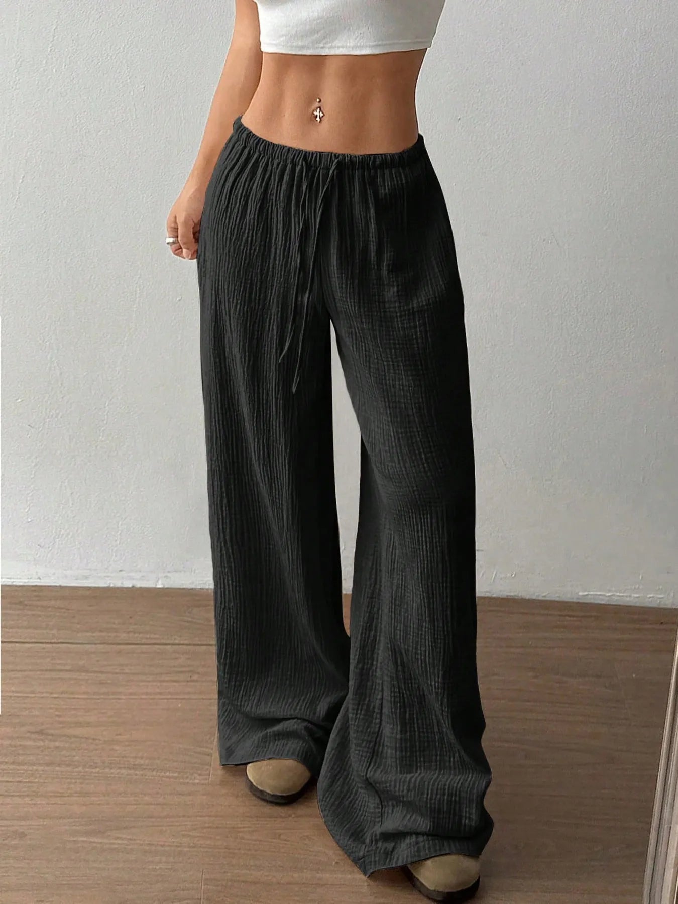 Person wearing black wide-leg pants against a plain background