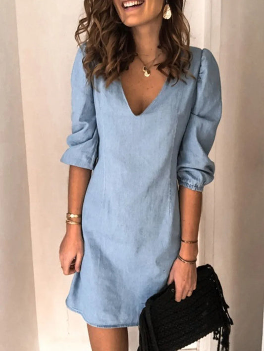 Woman wearing a light blue dress with long sleeves against a plain background