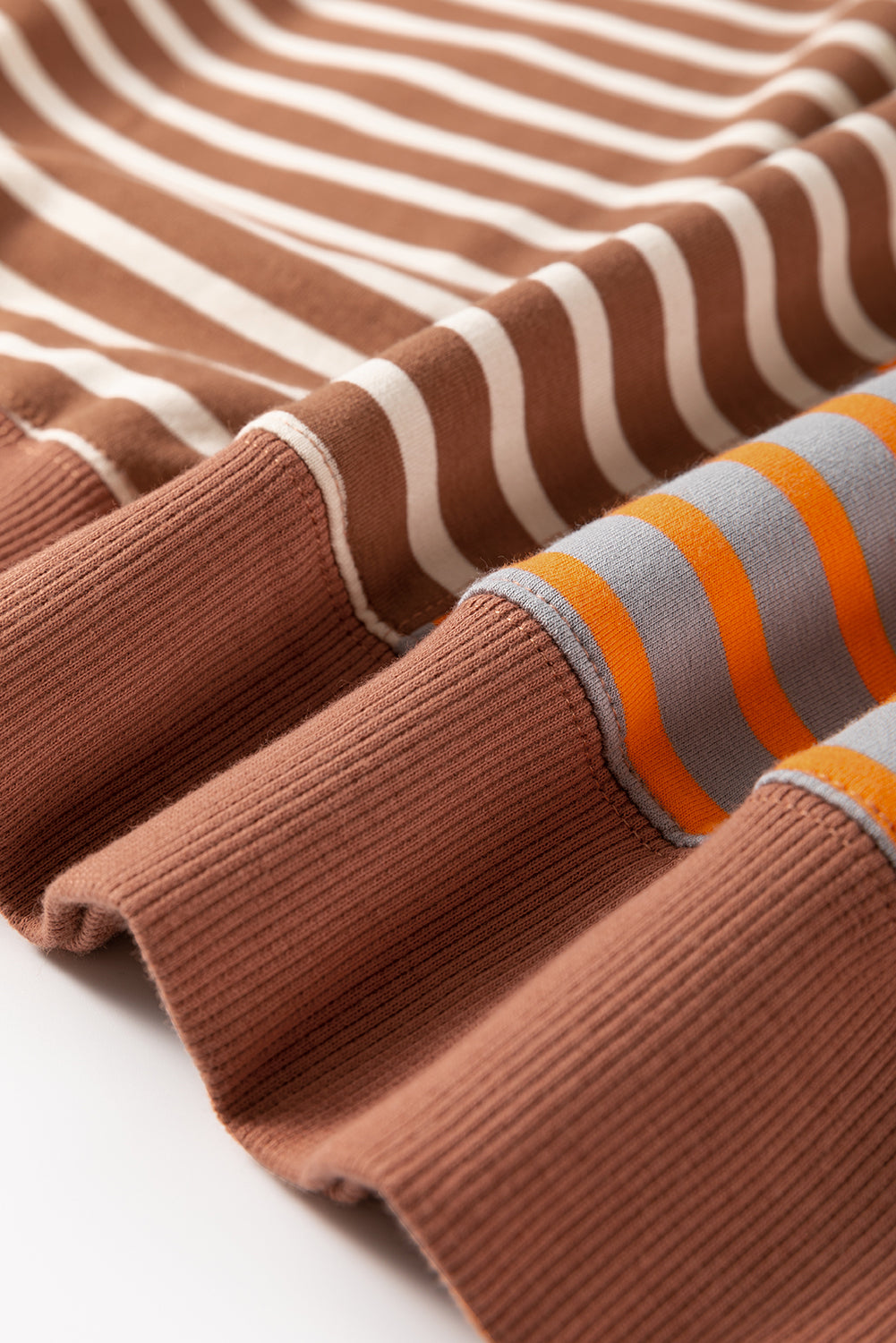 Close-up of striped fabric with brown, white, orange, and gray colors on a white background.
