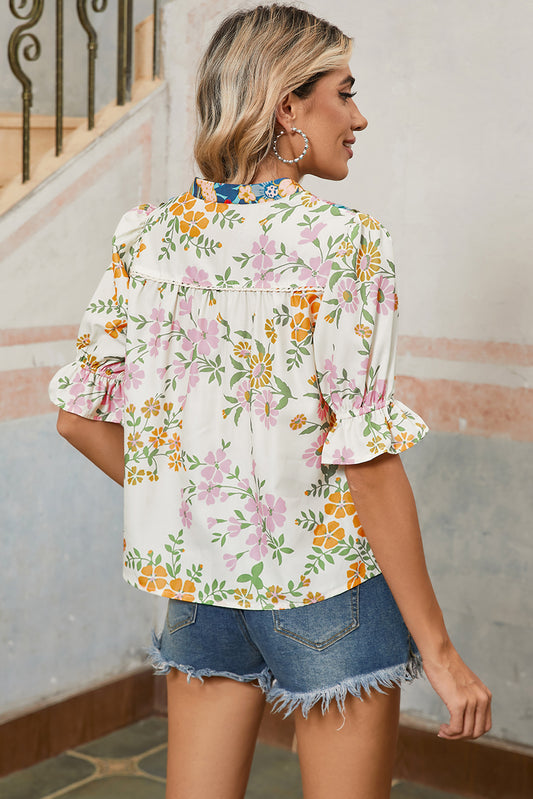 Woman wearing a floral blouse and denim shorts in an indoor setting.