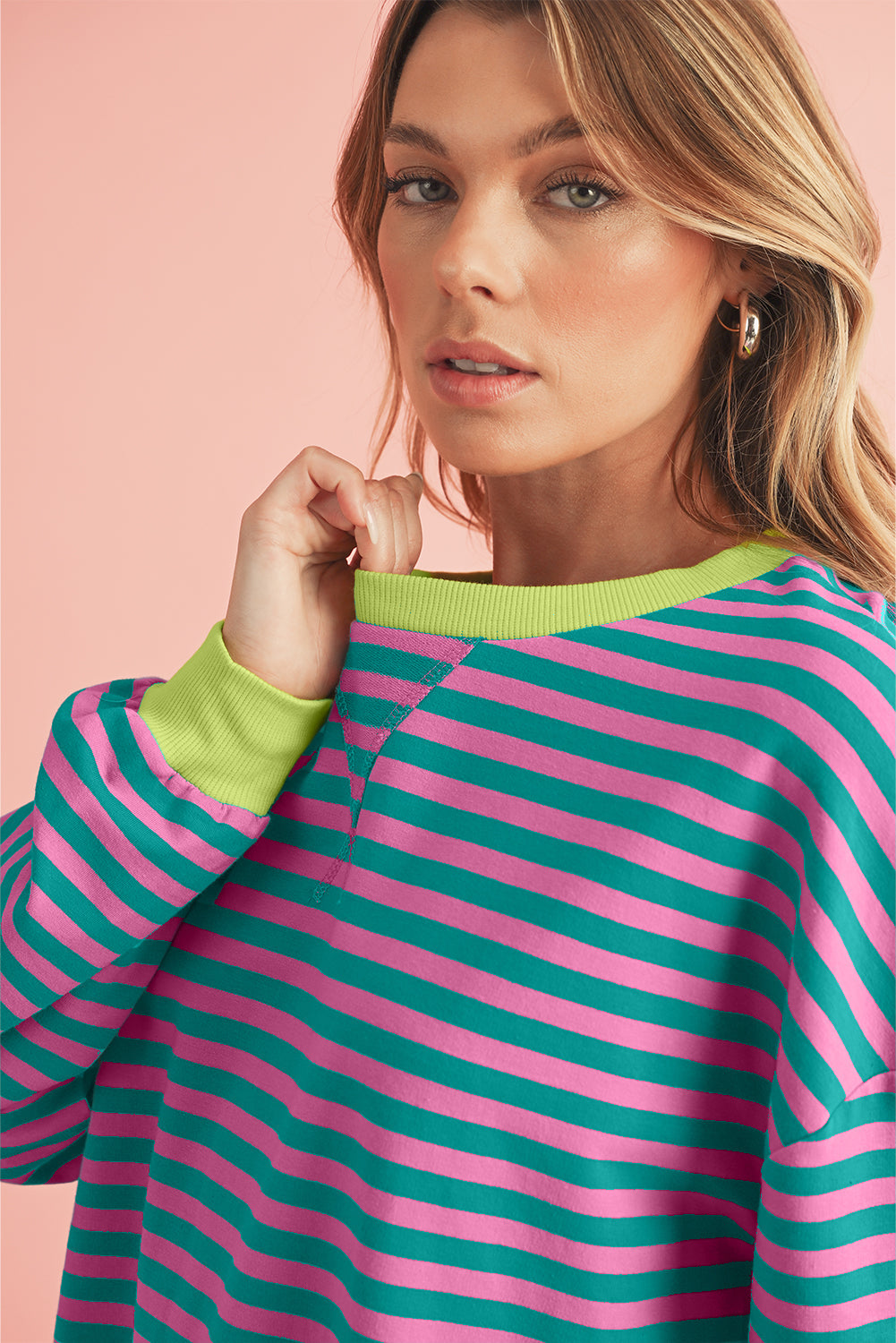 Woman wearing a colorful striped sweater against a pink background