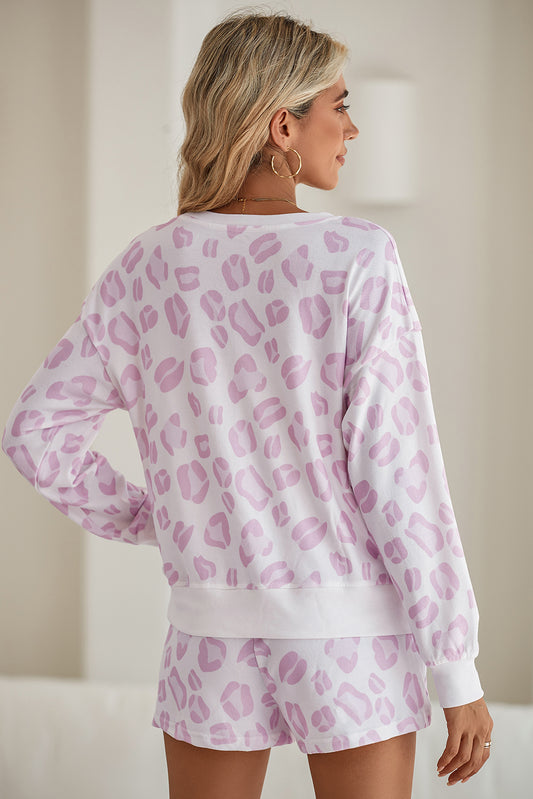 Woman wearing a pink leopard print pajama set against a neutral background