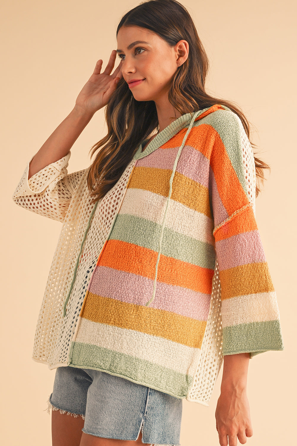 Woman wearing a colorful striped sweater with a beige background