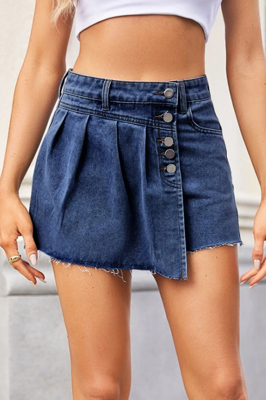 Person wearing a blue denim skirt with button details on a neutral background