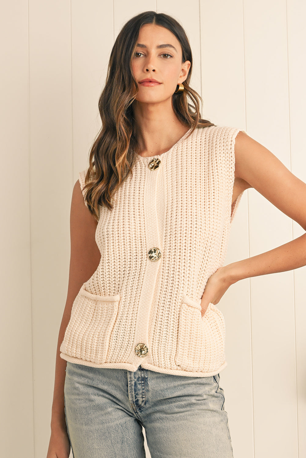 Woman wearing a beige knitted vest with a white background