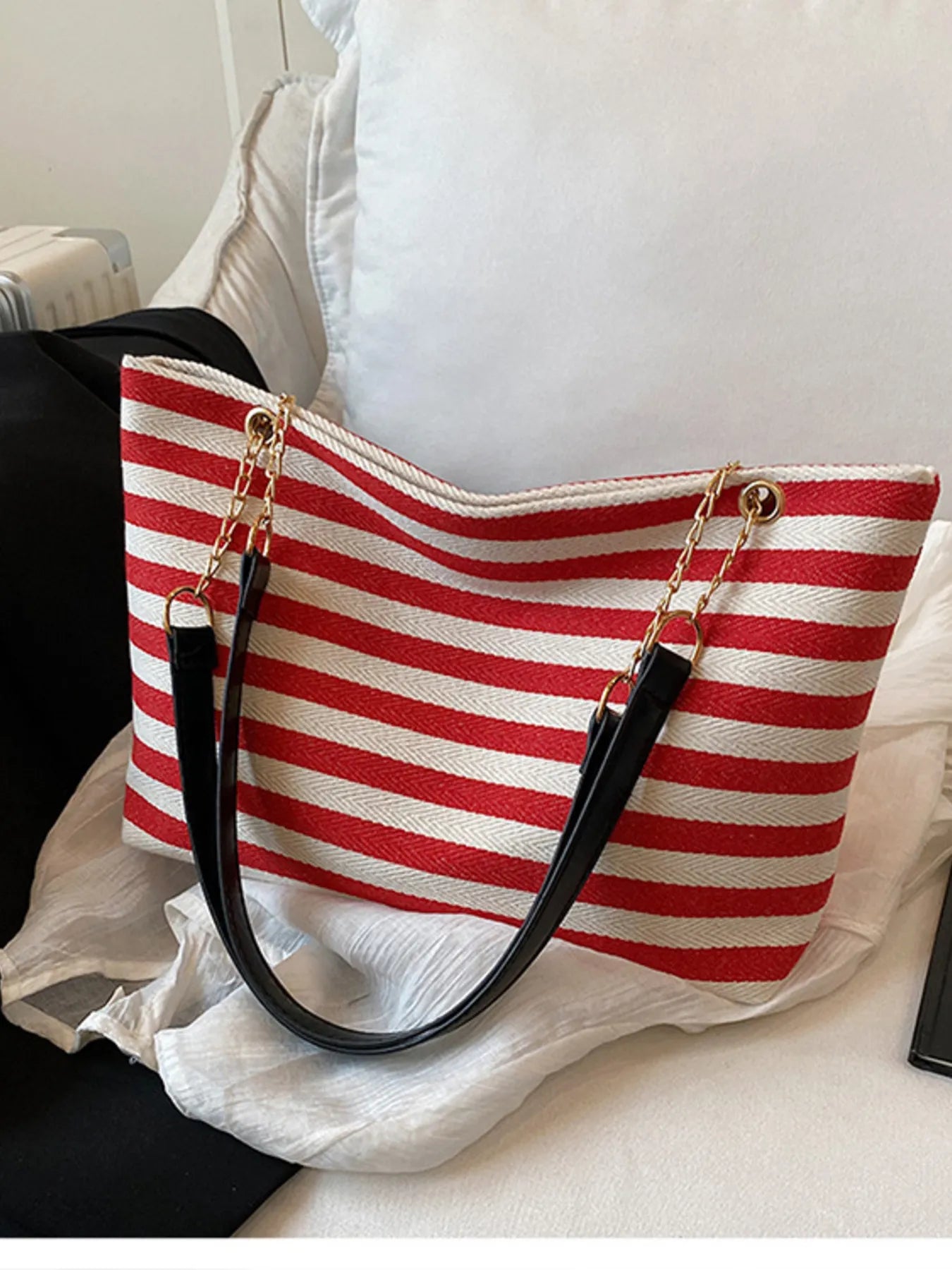 Red and white striped handbag with black handles on a white surface
