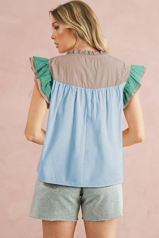 Woman wearing a two-tone top with green and blue sleeves on a pink background