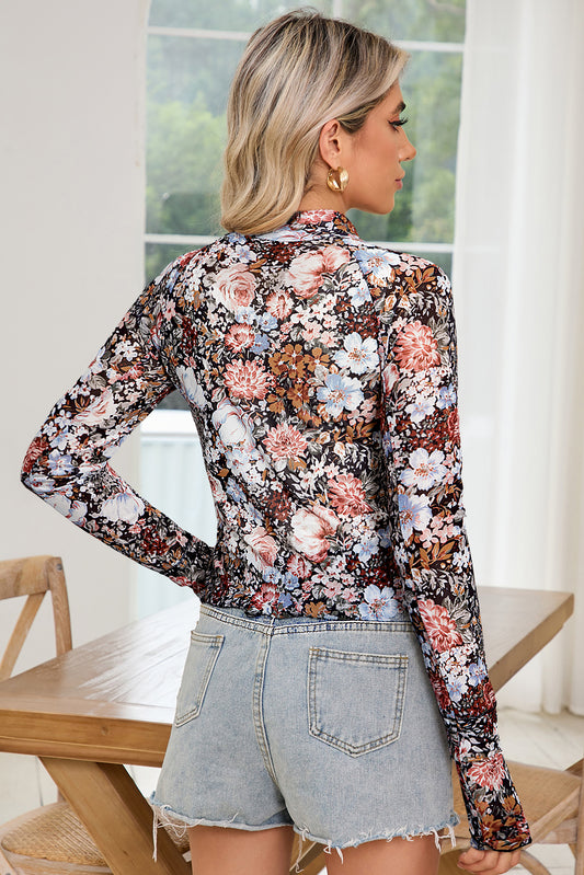 Woman wearing a floral blouse and denim shorts indoors.