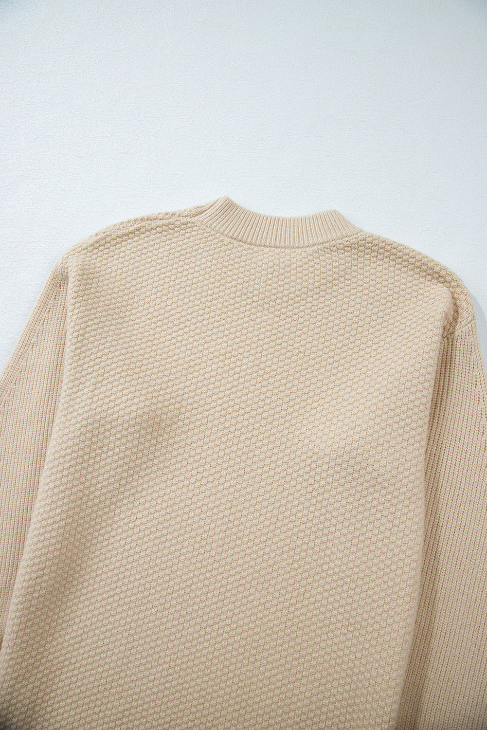Beige knitted sweater on a light gray background