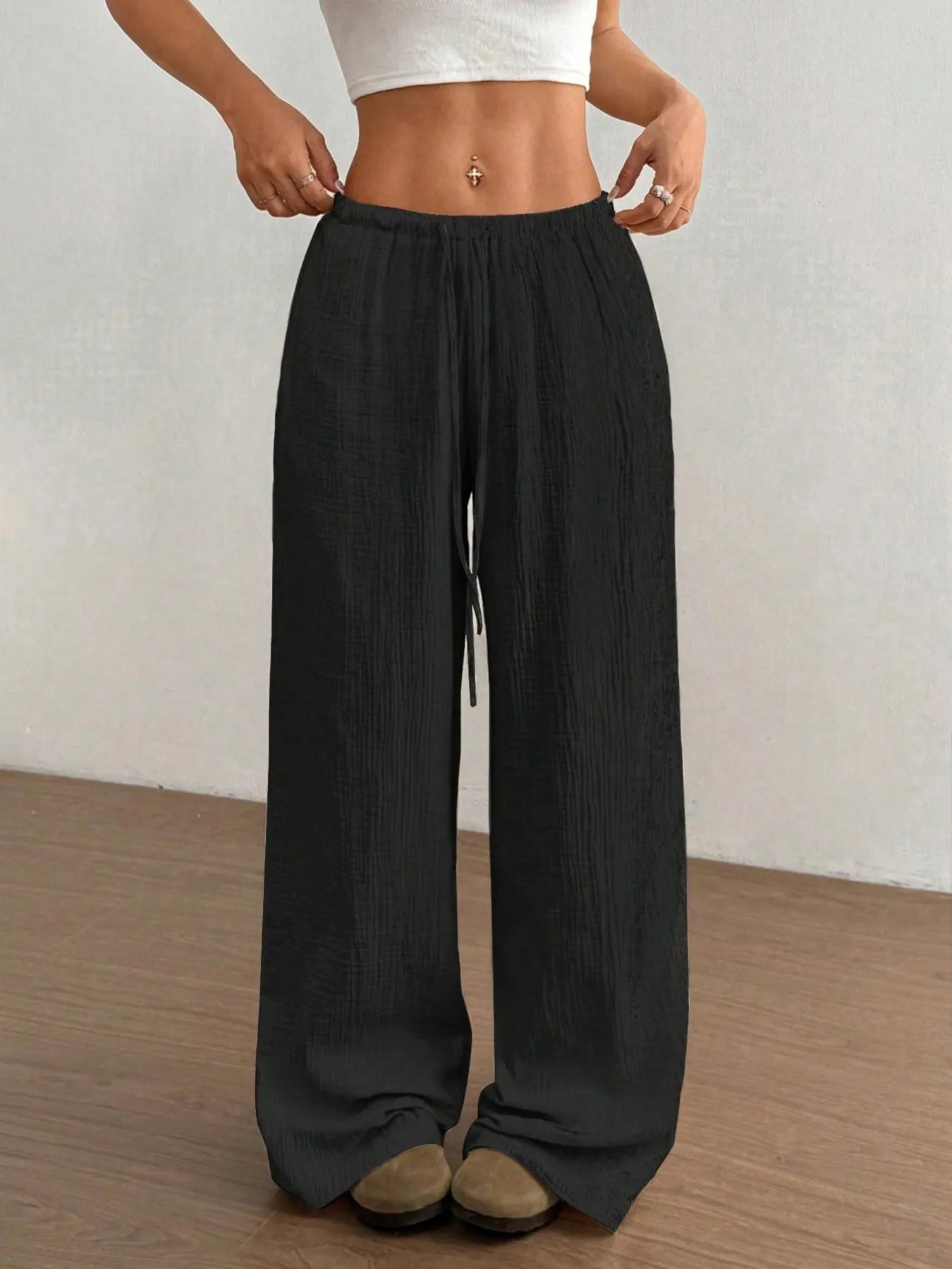 Person wearing black wide-leg pants on a plain background