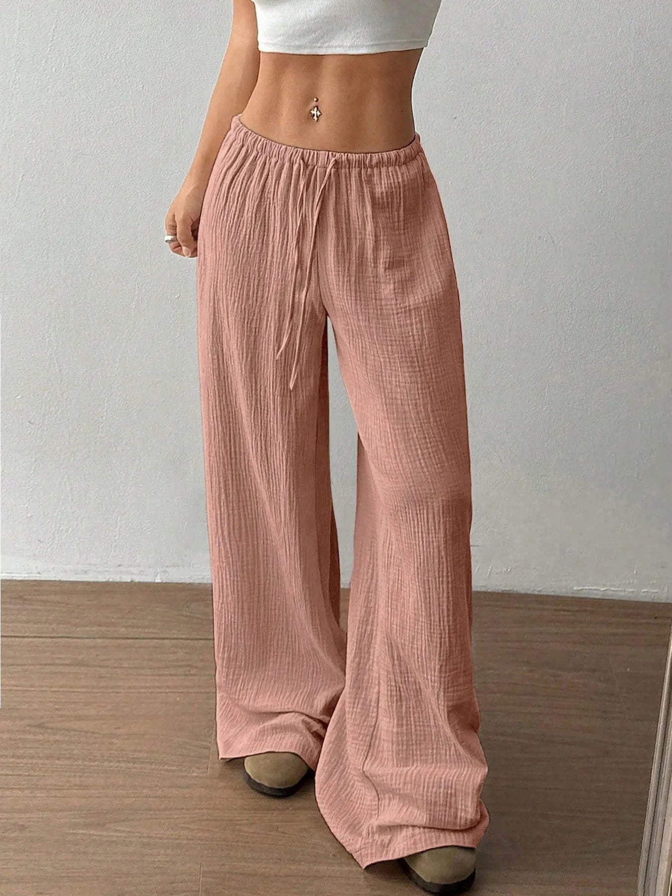 Person wearing pink wide-leg pants against a plain background