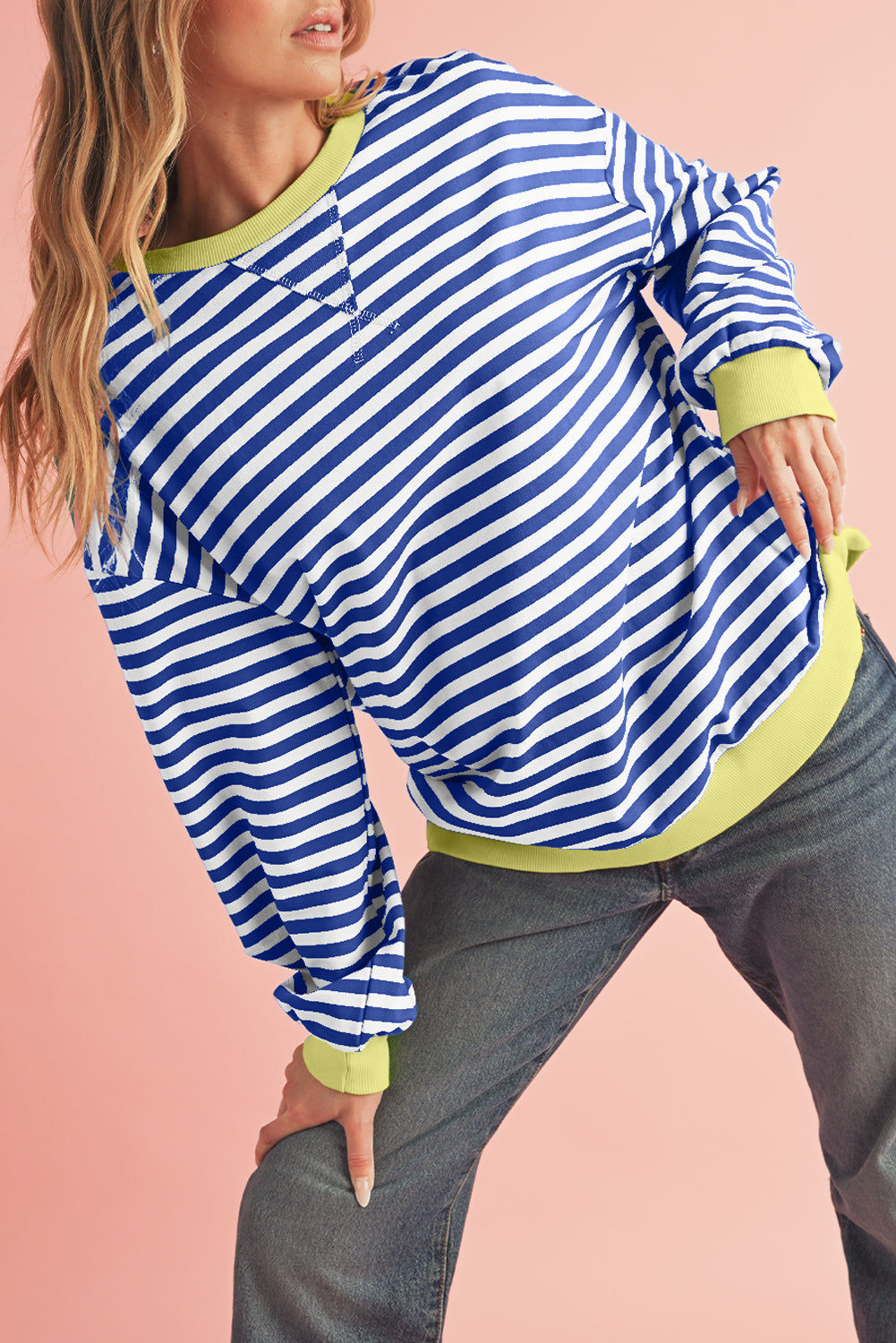 Person wearing a blue and white striped shirt with green accents on a pink background