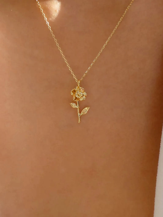 Gold rose necklace on a person's neck against a neutral background