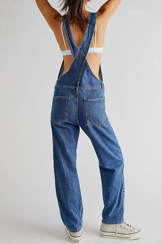 Person wearing blue denim overalls on a plain background