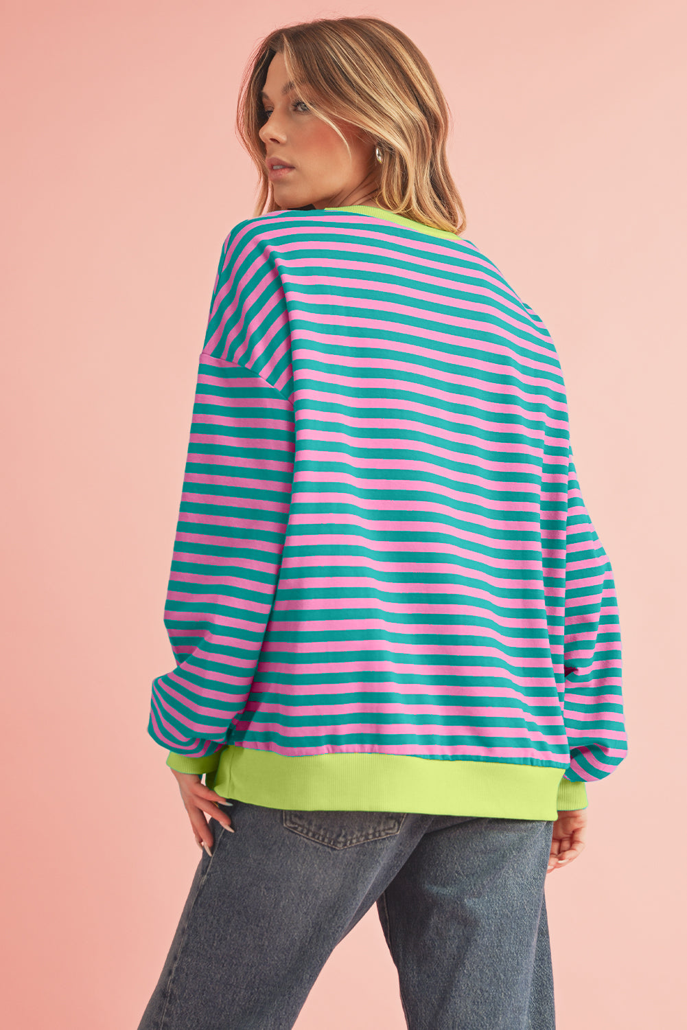 Person wearing a colorful striped sweater with a pink background