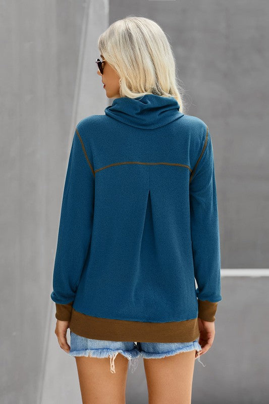 Person wearing a blue jacket with brown accents against a gray background