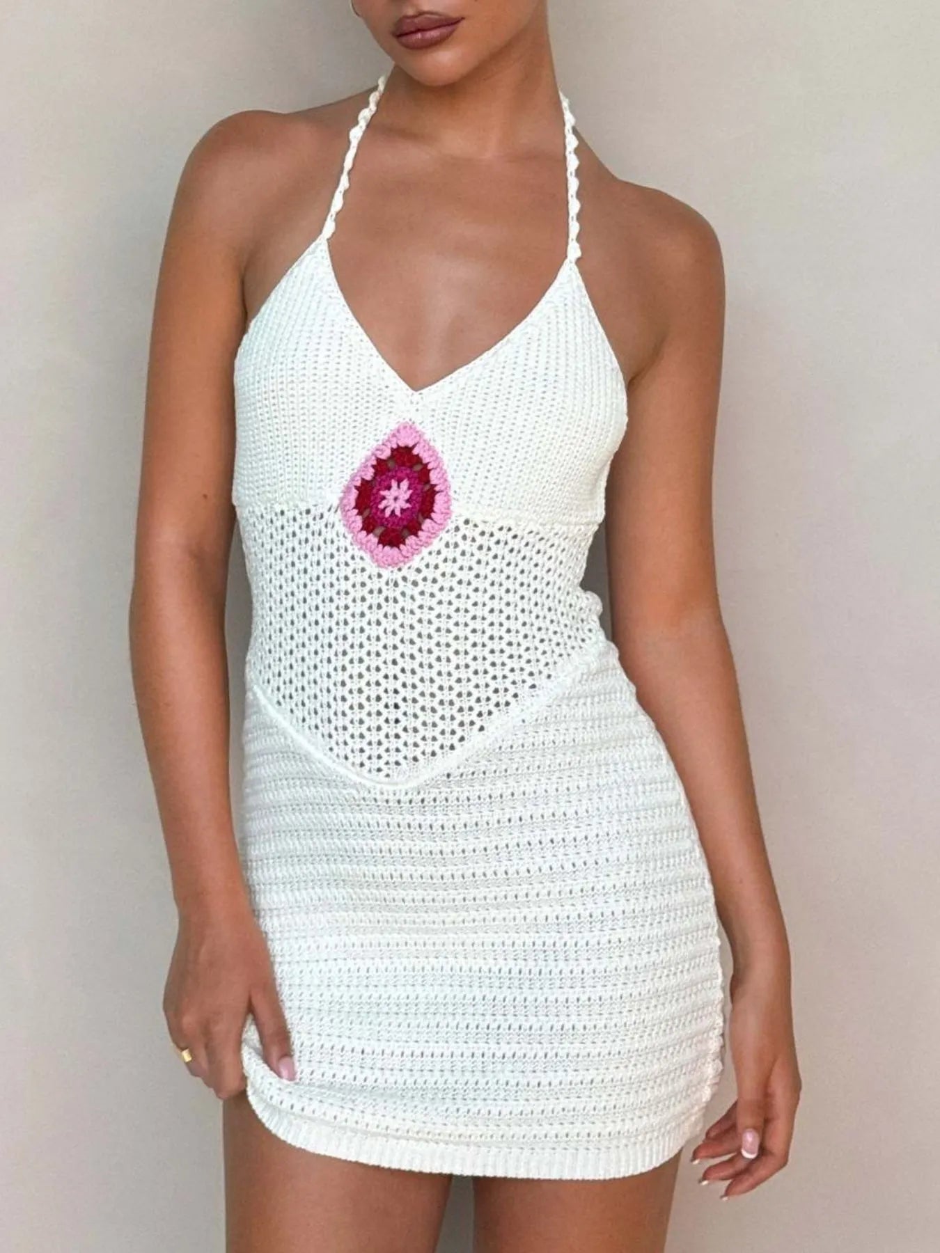 White crochet dress with a pink flower design on a plain background