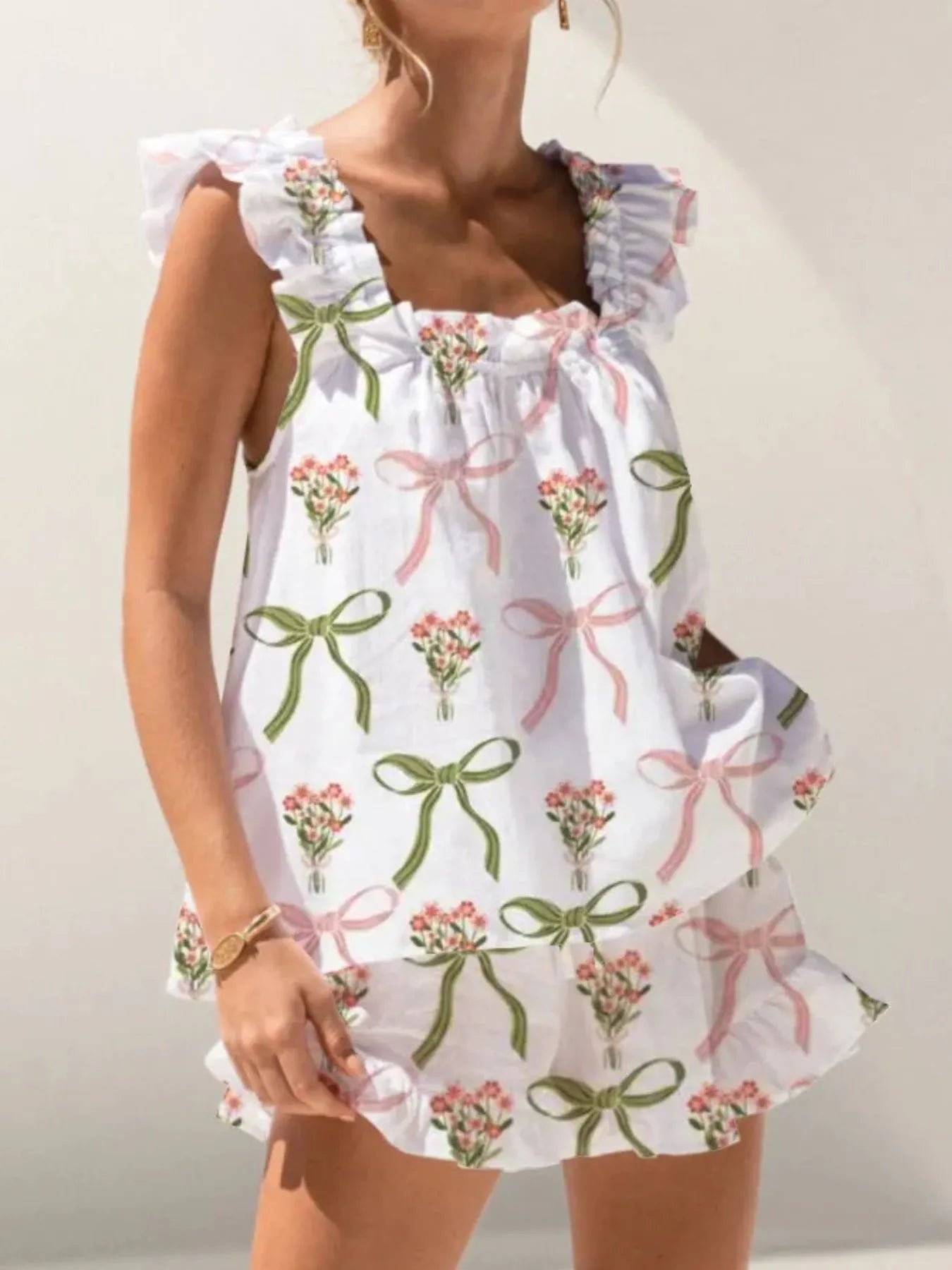 Woman wearing a white dress with pink floral and green bow patterns.