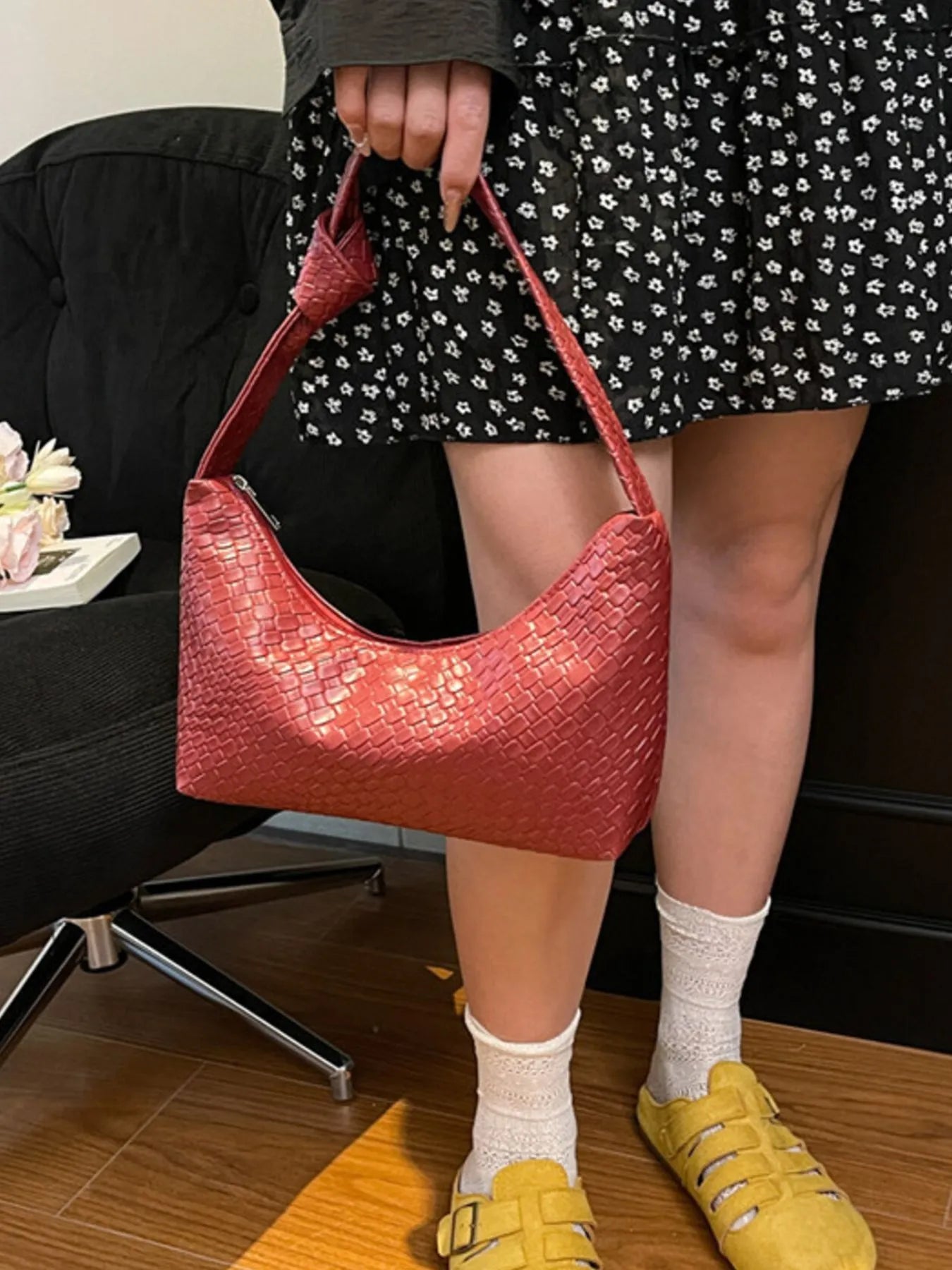 Person holding a red textured handbag indoors