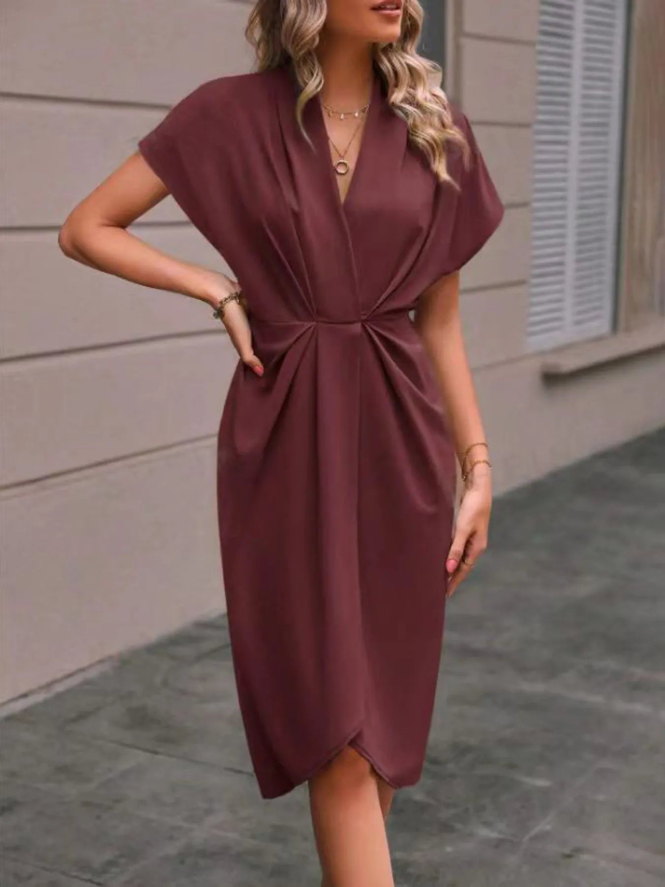 Woman wearing a burgundy dress standing on a sidewalk.