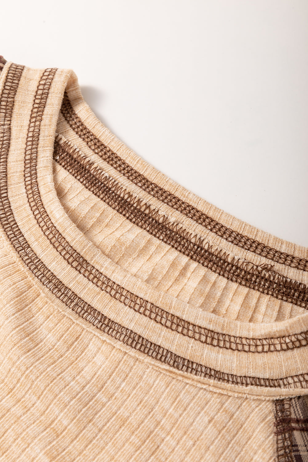 Close-up of a beige garment with brown stitching on a white background