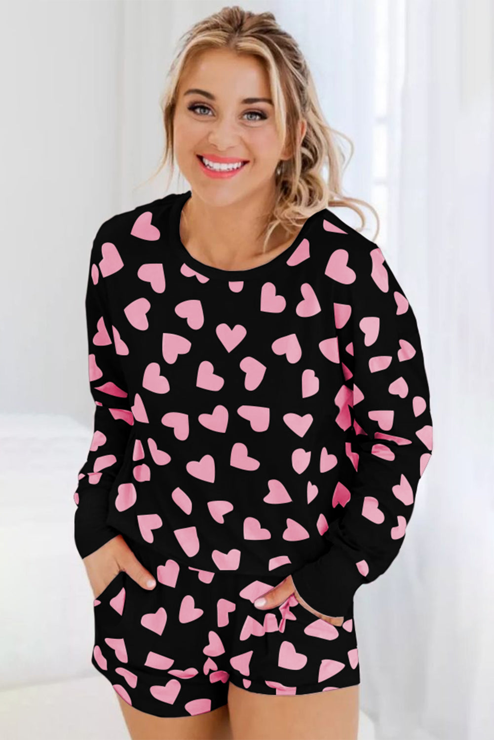 Woman wearing a black outfit with pink heart patterns against a white background