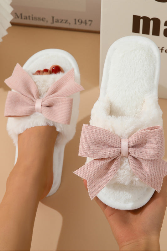 White slippers with pink bows on a beige background