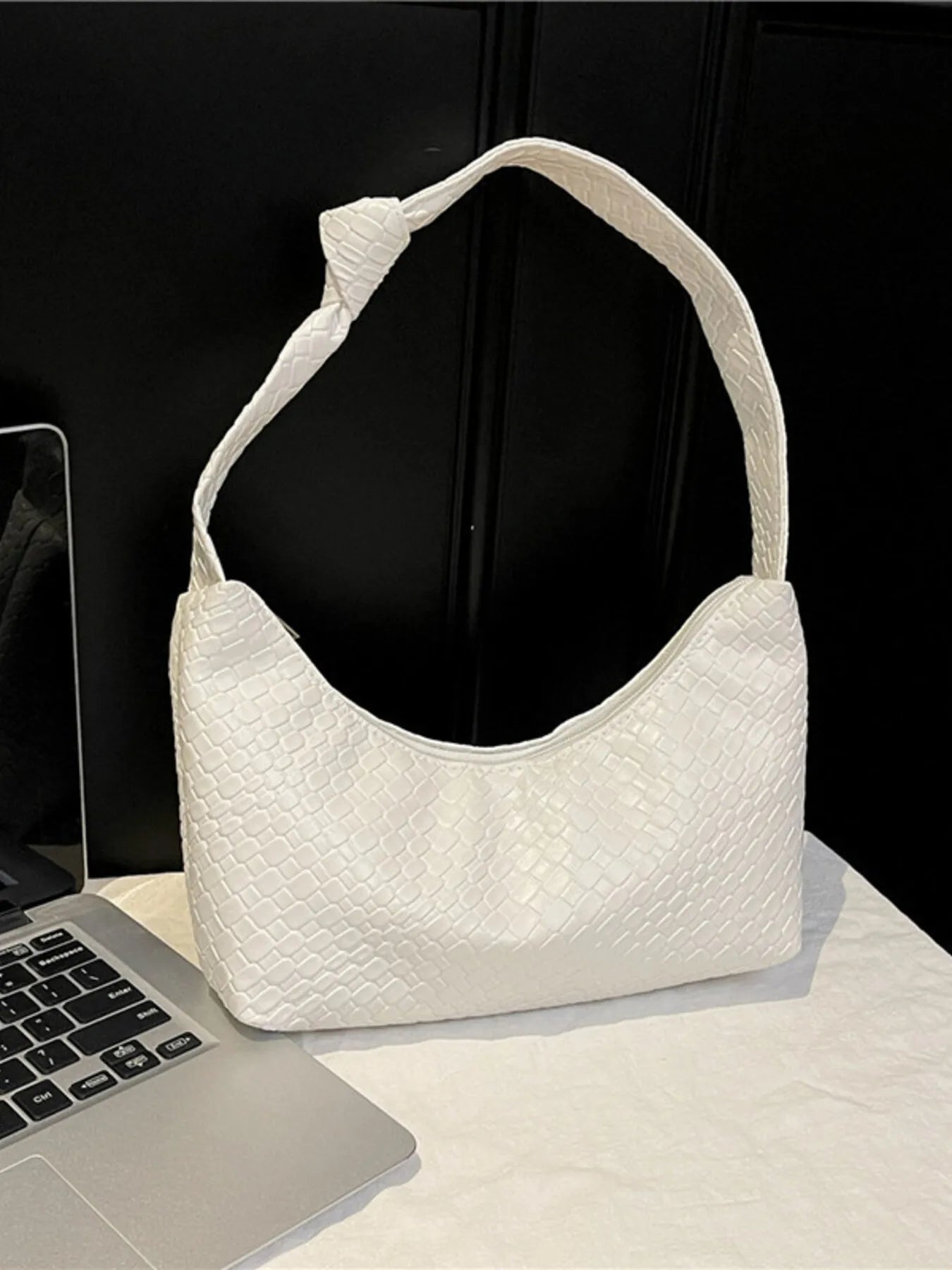 White textured handbag on a light surface with a black background